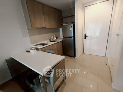 Modern compact kitchen with sleek cabinetry and stainless steel appliances in a stylish apartment.