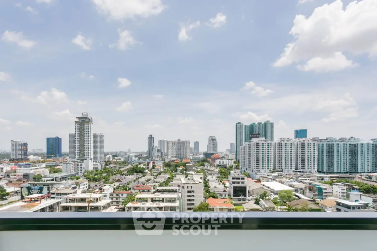 Stunning cityscape view from a high-rise balcony showcasing urban skyline and blue skies.