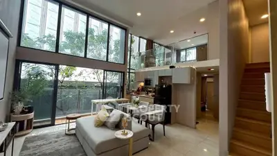Luxurious modern living room with high ceilings and large windows, featuring open kitchen and elegant decor.