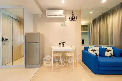 Modern living room with blue sofa, dining table, and mirrored wall