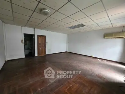 Spacious empty room with parquet flooring and air conditioning, ideal for customization.