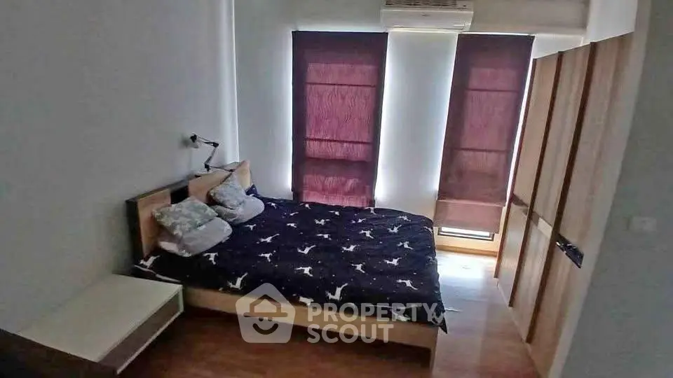 Cozy bedroom with modern furnishings and ample natural light from large windows.
