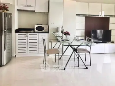 Modern kitchen with sleek appliances and glass dining table in a stylish open layout.