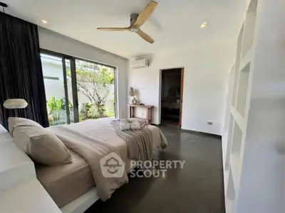 Modern bedroom with large window and garden view, featuring sleek design and cozy ambiance.
