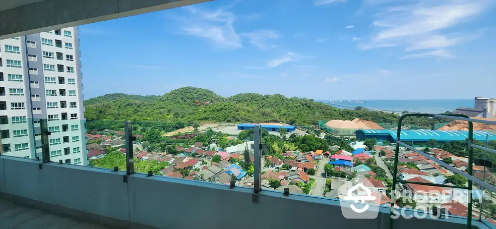 Stunning high-rise balcony view overlooking lush green hills and vibrant cityscape.