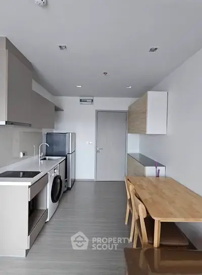 Modern kitchen with sleek appliances and dining area in open layout apartment.
