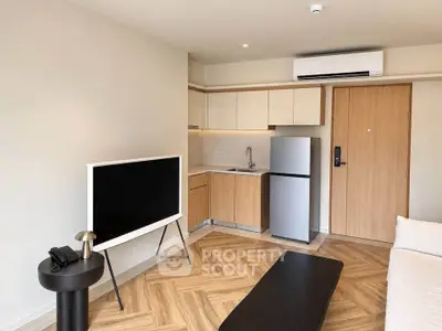 Modern living room with stylish kitchenette and sleek appliances in a cozy apartment.