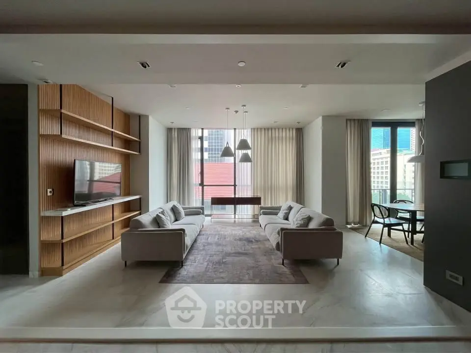 Spacious modern living room with elegant decor and city view, featuring sleek furniture and natural light.