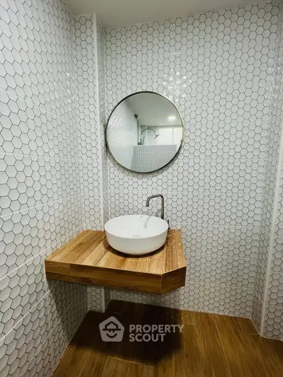 Modern bathroom with stylish round mirror and wooden countertop