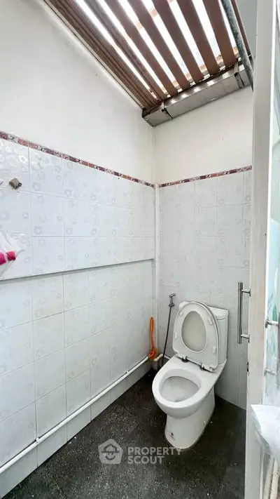 Compact bathroom with skylight and tiled walls, featuring a modern toilet.