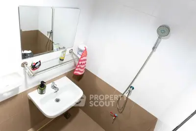Modern bathroom with sleek sink and shower, featuring stylish tiles and a large mirror.