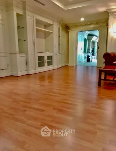 Spacious living room with elegant wooden flooring and classic built-in shelves.
