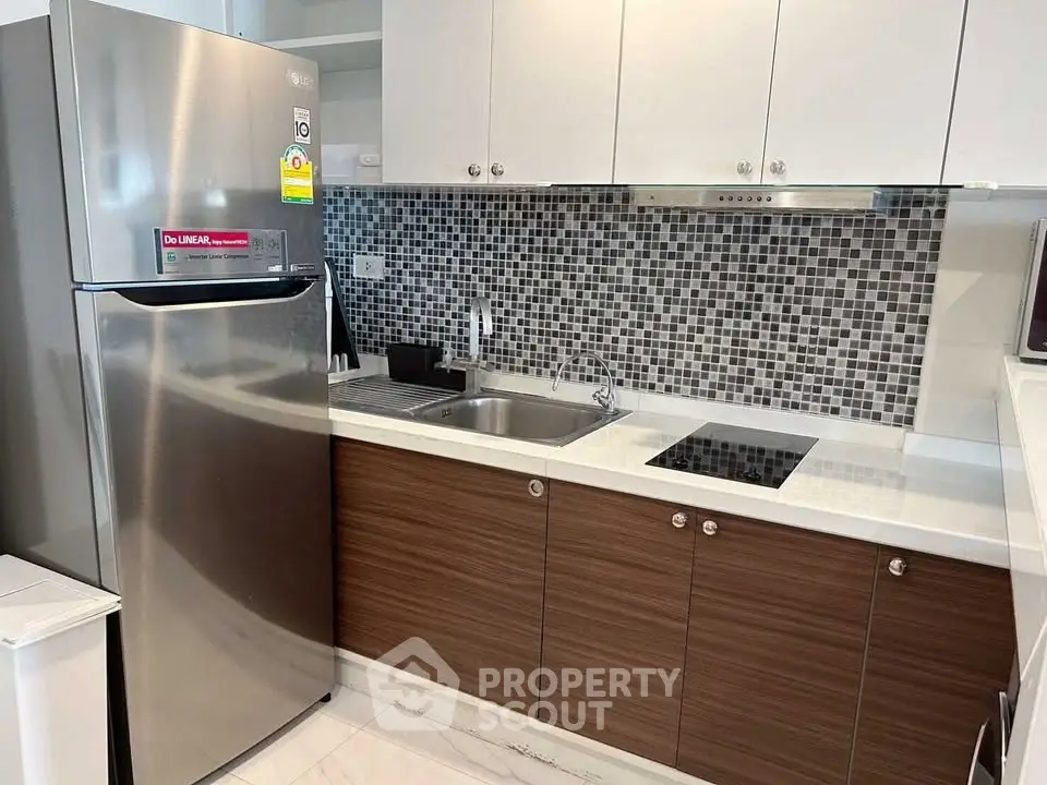 Modern kitchen with sleek cabinetry and stainless steel fridge in a stylish apartment.