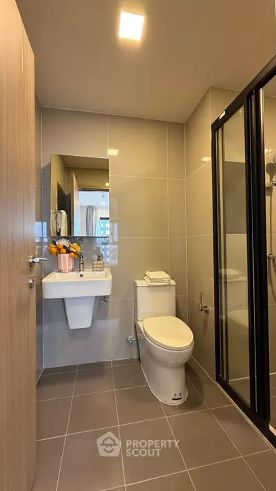Modern bathroom with sleek design, featuring a glass shower and elegant fixtures.