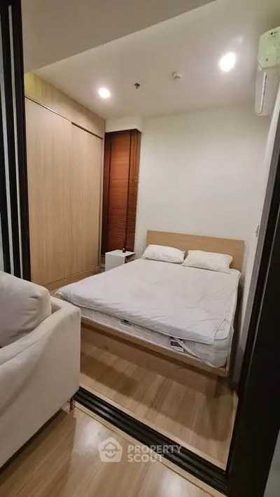 Cozy bedroom with wooden flooring and modern furnishings in a compact apartment.