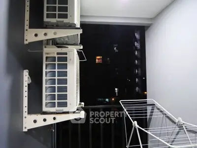 Compact balcony with air conditioning units and drying rack at night