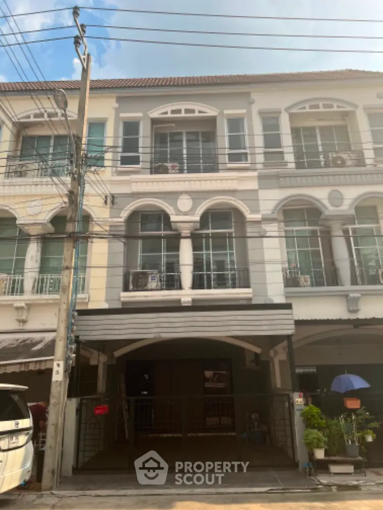 Charming townhouse facade with classic design elements, featuring arched windows and a secure carport, nestled in a vibrant neighborhood.