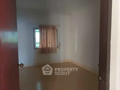 Spacious empty room with tiled floor and window, ideal for customization.