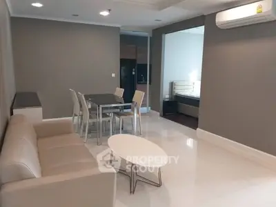 Spacious modern living room with sleek furniture and dining area in open layout apartment.