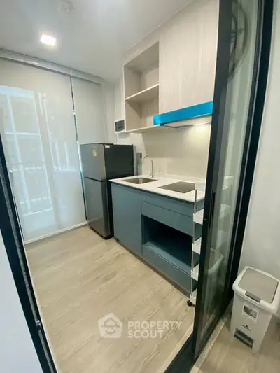 Modern compact kitchen with sleek design and appliances in a contemporary apartment.