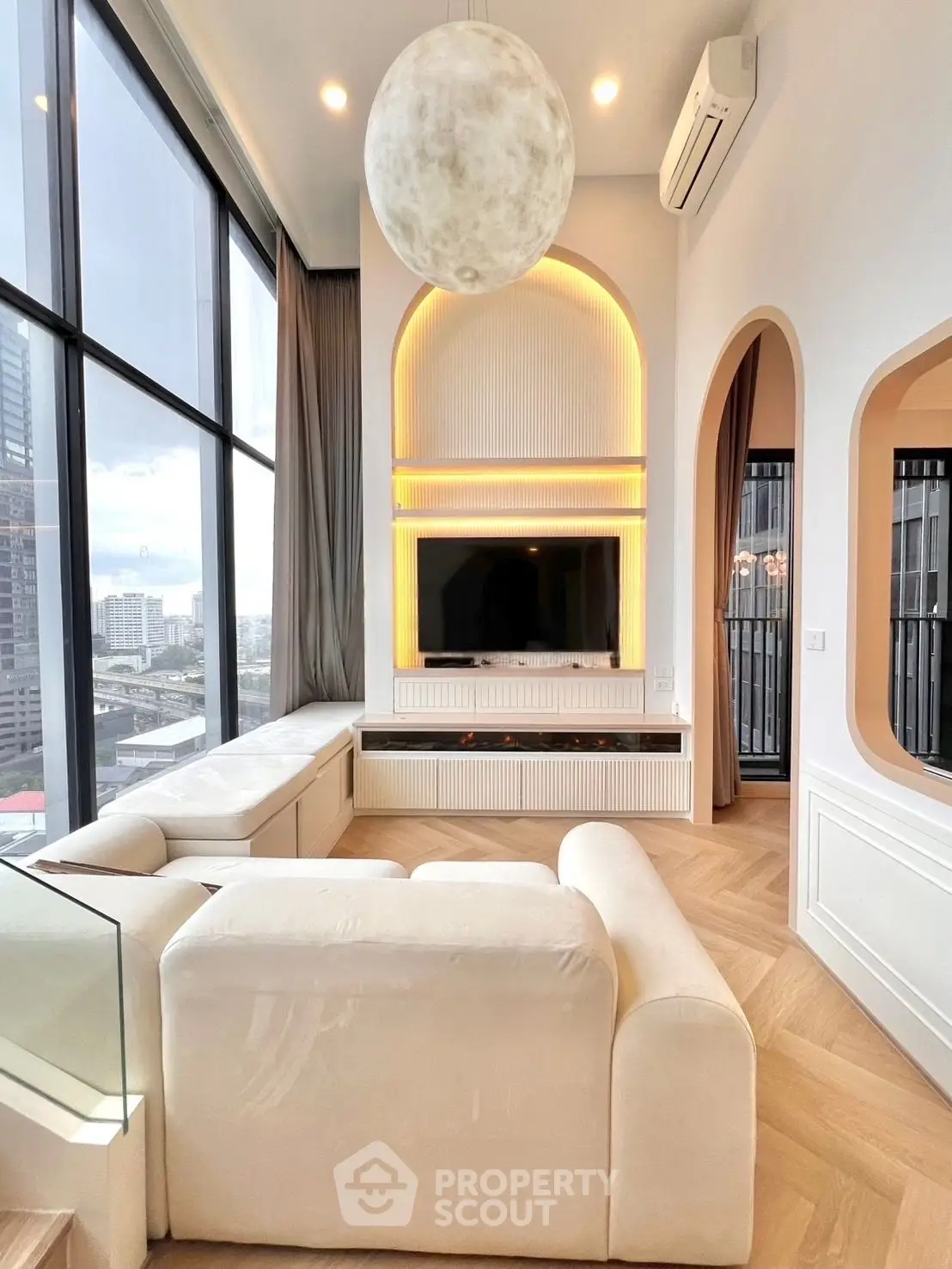 Luxurious modern living room with large windows and city view, featuring elegant lighting and plush seating.