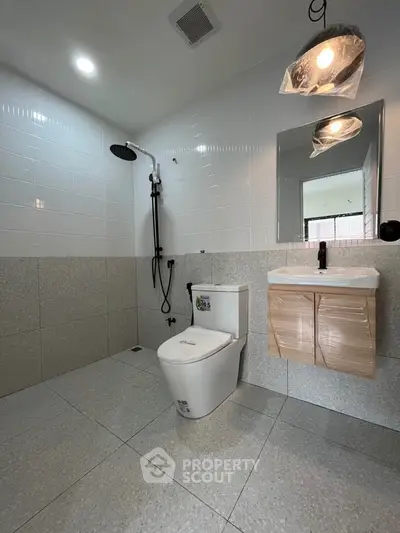 Modern bathroom with sleek fixtures and minimalist design, featuring a rain shower and contemporary vanity.