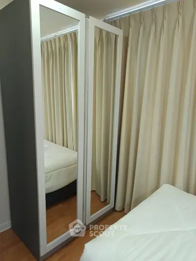 Cozy bedroom with mirrored wardrobe and elegant curtains