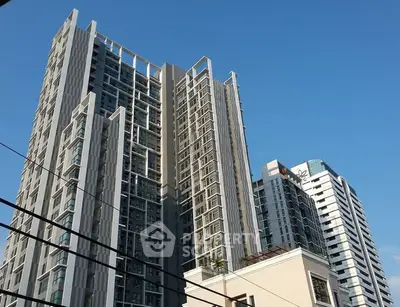 Modern high-rise residential buildings with sleek architecture against a clear blue sky.