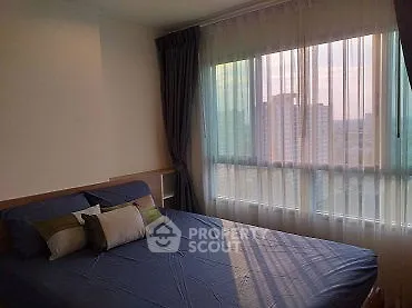 Cozy bedroom with large window offering city view, featuring stylish bedding and elegant curtains.