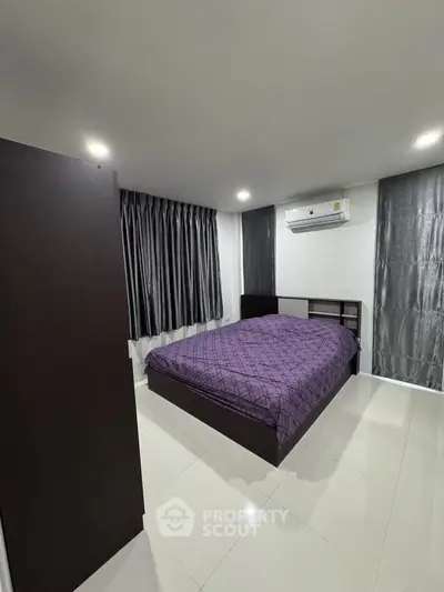 Modern bedroom with sleek design and air conditioning, featuring a comfortable bed and stylish curtains.
