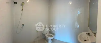 Spacious bathroom with shower, toilet, and sink in a modern white-tiled design.