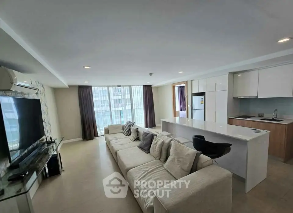 Spacious modern living room with open kitchen and large windows in a luxury apartment.