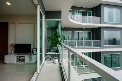 Modern apartment with spacious balcony and city view, featuring sleek design and large glass doors.