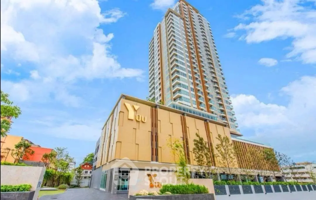 Stunning modern high-rise building with lush landscaping and clear blue sky.