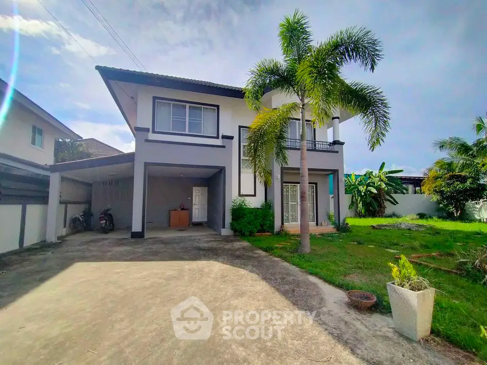 Spacious two-story house with lush garden and driveway in tropical setting