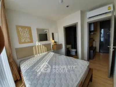 Cozy bedroom with modern decor and ensuite bathroom, featuring natural light and wooden flooring.