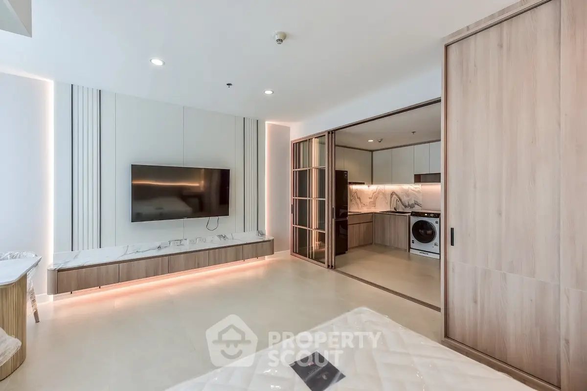 Modern living room with open kitchen and built-in appliances in luxury apartment.