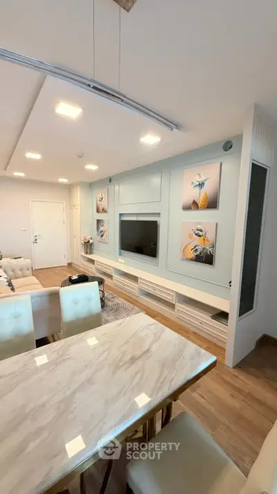 Modern living room with elegant decor and stylish furniture, featuring a sleek TV setup and contemporary artwork.