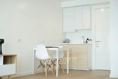 Modern minimalist kitchen with white cabinets and wooden accents in a cozy apartment.