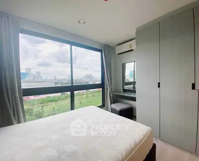 Bright bedroom with large window offering stunning city view, modern decor, and ample natural light.