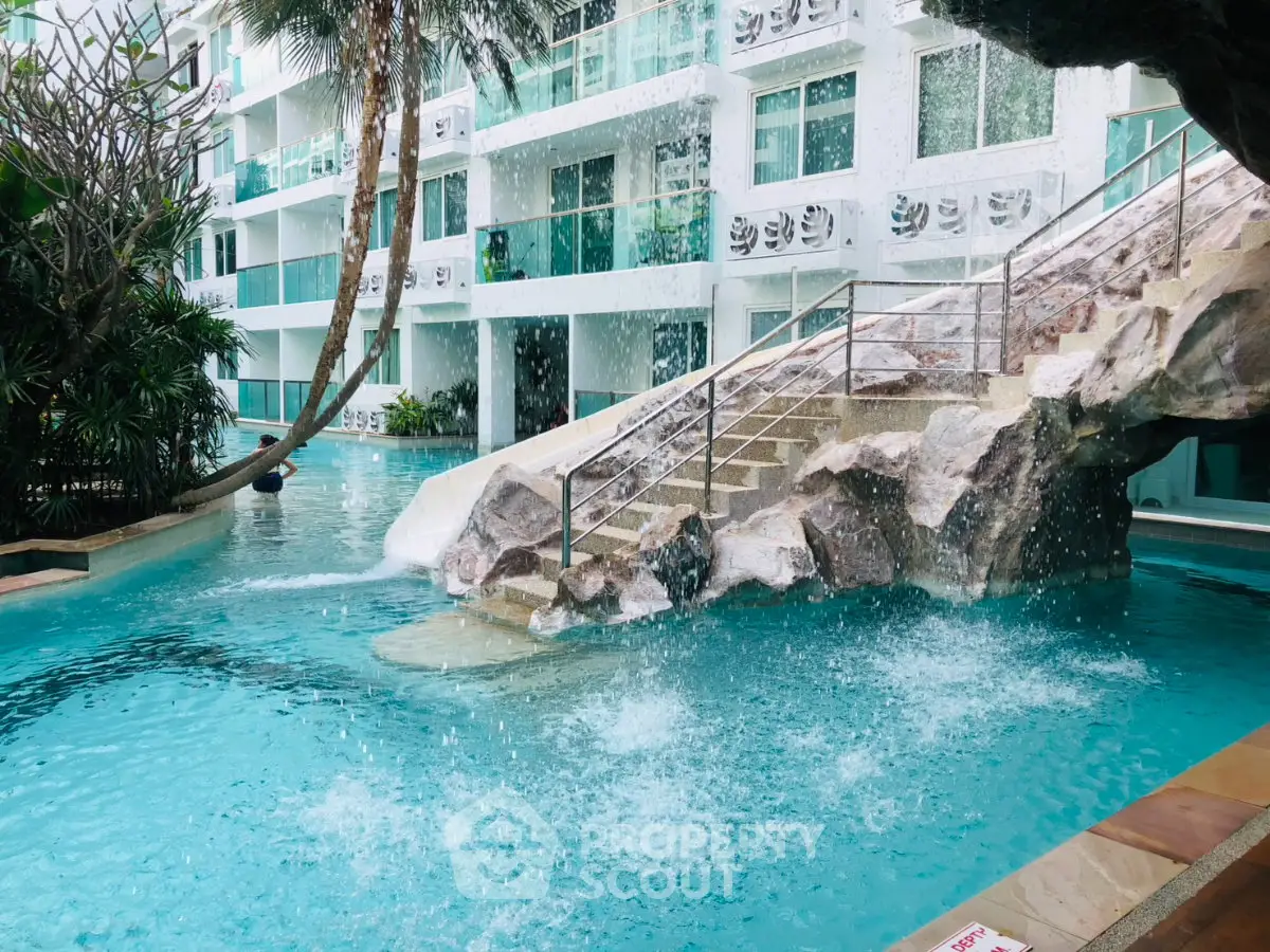 Luxurious pool area with waterfall feature in modern residential complex.