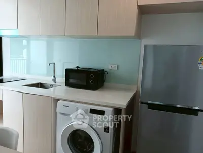 Modern kitchen with sleek appliances including washing machine and fridge, ideal for urban living.