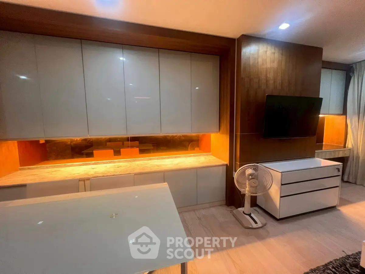 Modern living room with sleek cabinetry and mounted TV, featuring warm lighting and contemporary design.