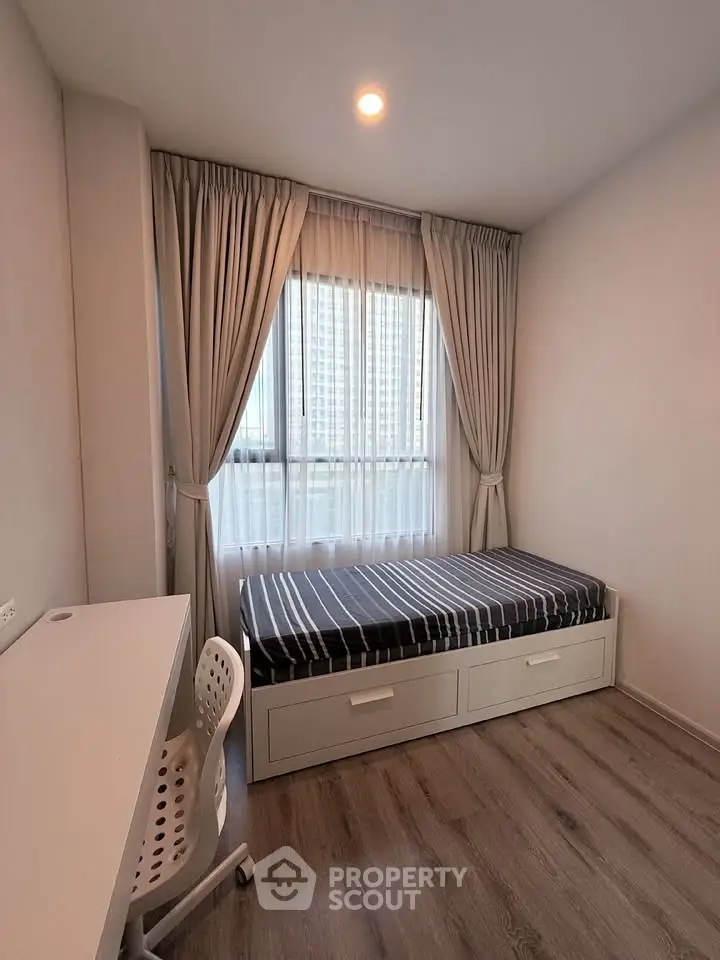 Cozy bedroom with single bed, study desk, and large window with city view.