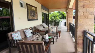 Charming covered balcony with cozy seating and lush garden view.