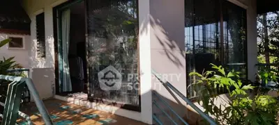 Charming balcony with lush greenery and large glass doors in a serene setting.