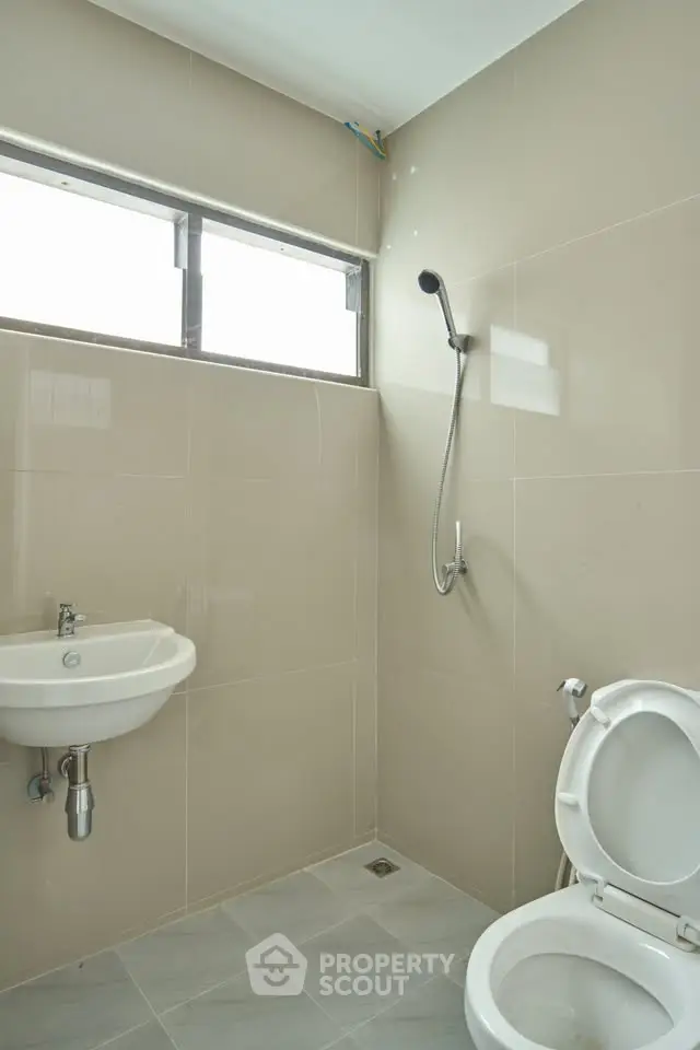 Modern minimalist bathroom with shower and sink in neutral tones.