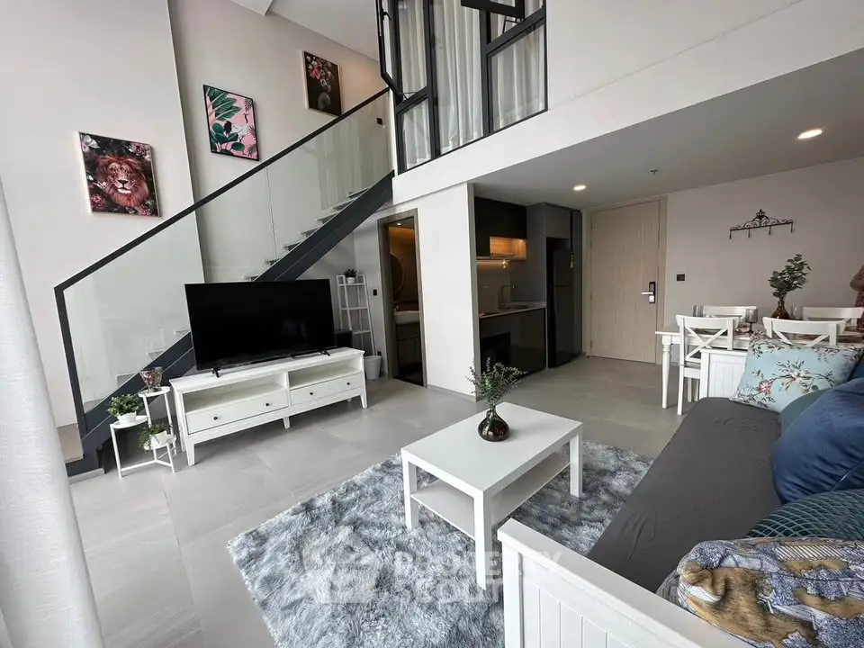 Modern duplex living room with stylish decor and open layout, featuring a staircase and cozy seating area.