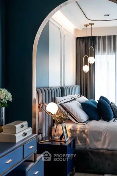Luxurious bedroom with elegant decor and modern lighting, featuring plush bedding and stylish blue accents.
