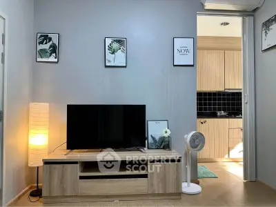 Modern living room with sleek TV stand and stylish decor, adjacent to a cozy kitchen area.